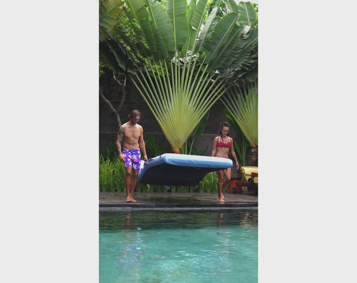 Couple laying side by side on the ACQUABOSS Luxe Double Lounger, floating in the pool and relaxing under the sun