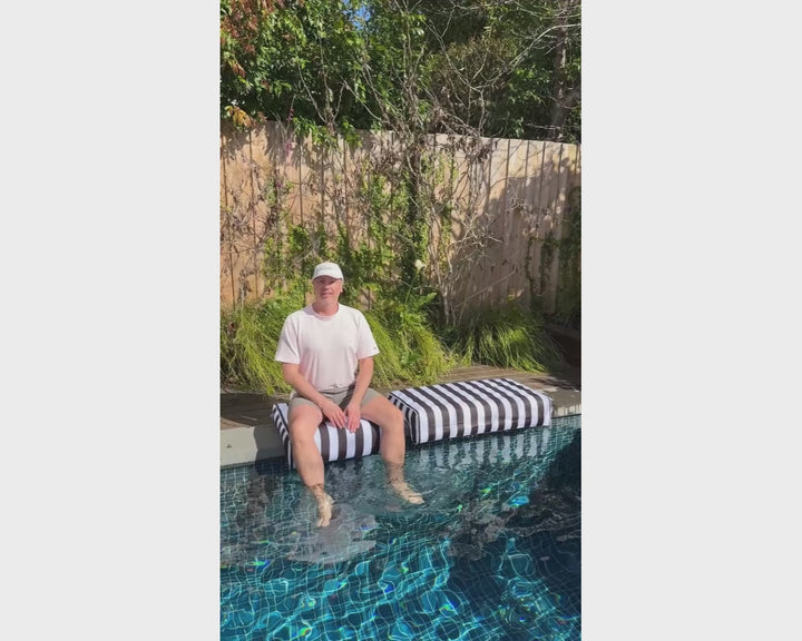 ACQUABOSS black and white inflatable pool edge cushion for comfortable poolside seating, providing a soft place to sit and relax with your legs in the water.