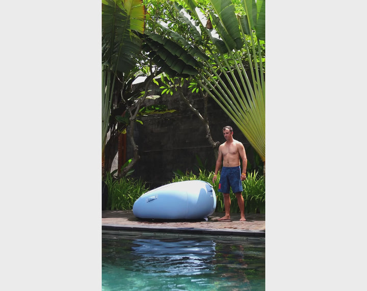 video of a Man lounging on the Blue Luxe ACQUABOSS Daydreamer inflatable bed in a pool, splashing water with his foot while relaxing