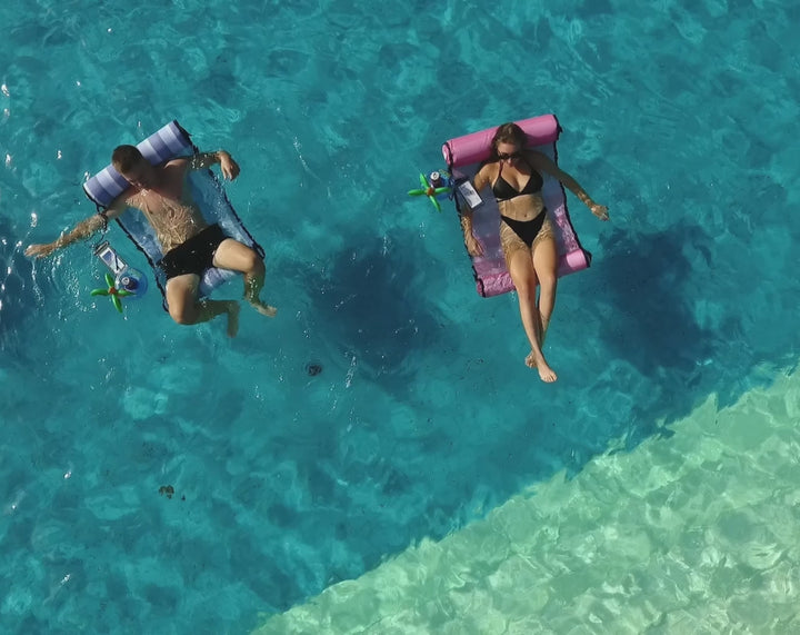 video of two people relaxing on ACQUABOSS floating water hammocks in a clear blue pool, each with an inflatable headrest, drink holder, and waterproof phone pouch